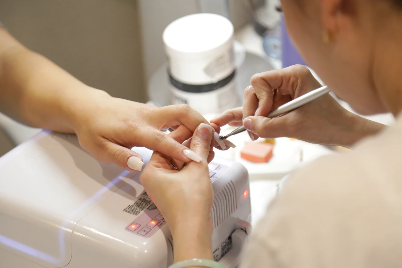 Nail technician shaping a nude manicure at a luxury nail salon in Elgin, TX